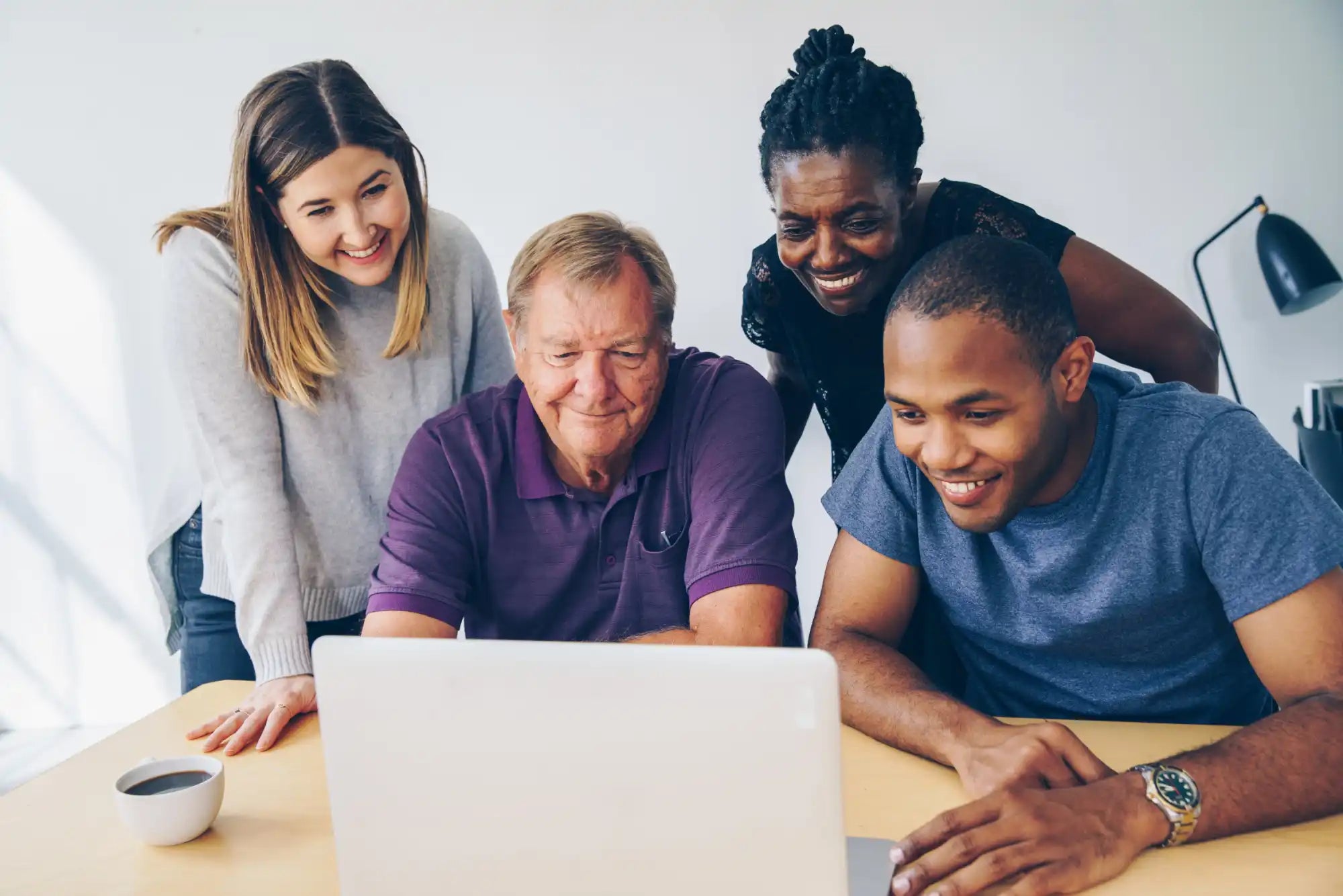 Smiling group looking at laptop.